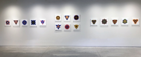 Sixteen works on paper by Jack Youngerman under plexi box frames installed on white walls