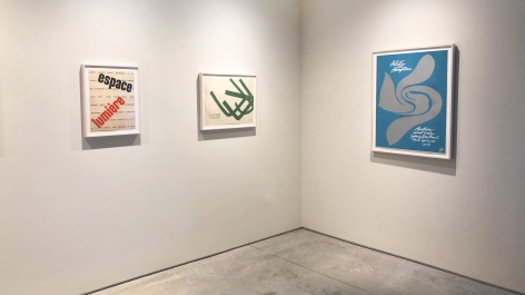 Installation view of three posters by Jack Youngerman.  Red and black graphics, green abstract form, and blue poster with grey form in center advertising "Artists in the Hamptons" exhibition