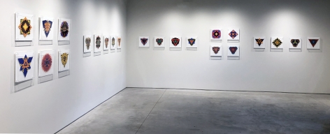 Twenty three works on paper by Jack Youngerman under plexi box frames installed on white walls at the Washburn Gallery